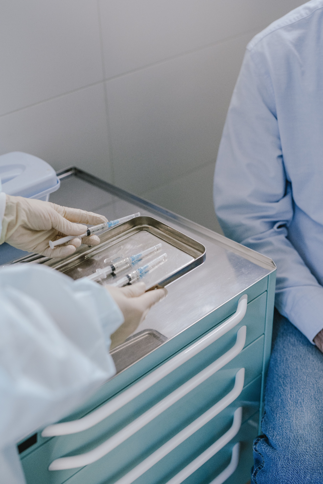 Healthcare professional preparing syringes on a sterile medical tray